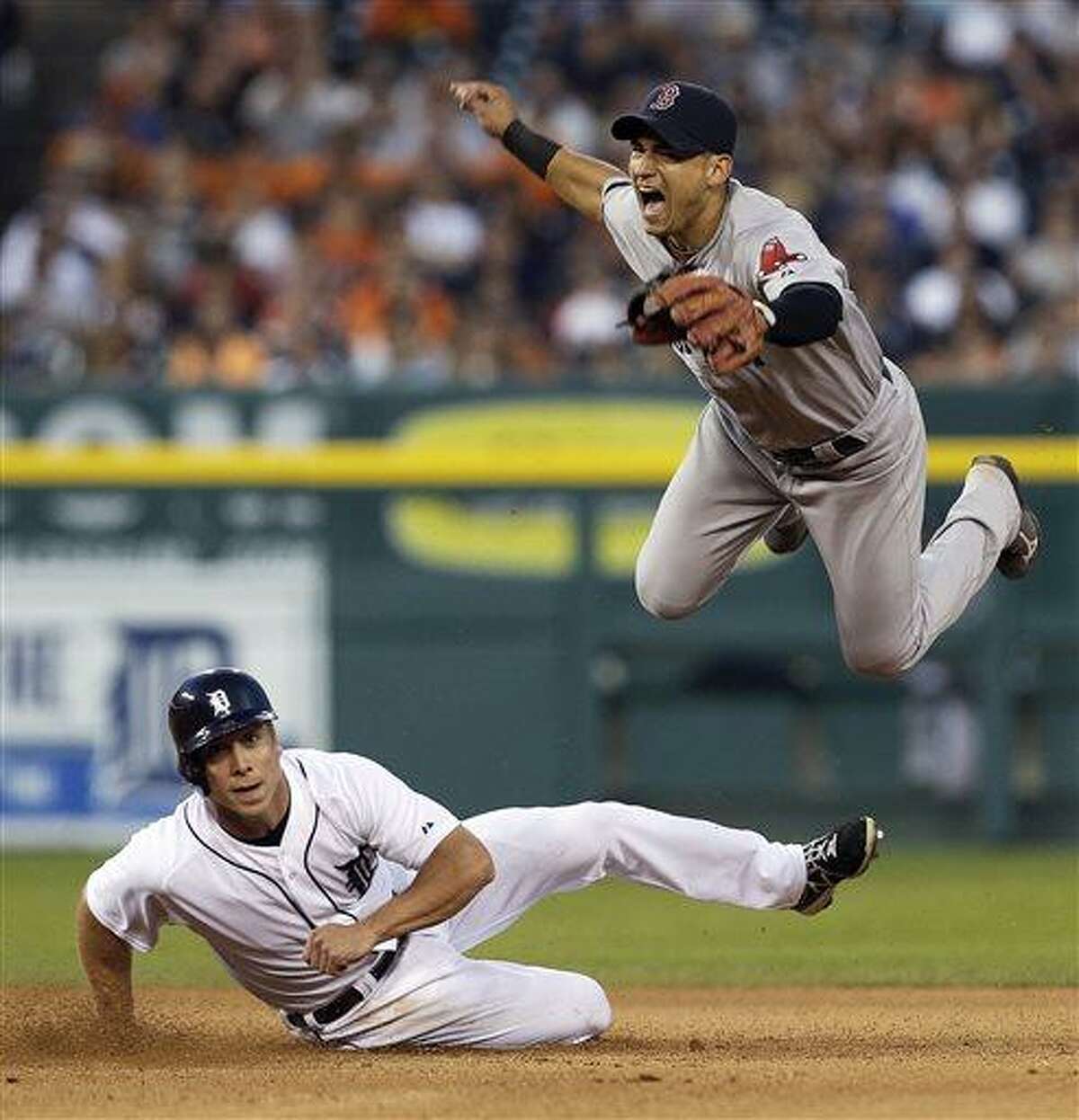 Boston Red Sox's Jose Iglesias jumps after Detroit Tigers' Andy Dirks, bottom, slides to break up the throw to first base on a Brayan Pena fielders choice in the seventh inning of a baseball game in Detroit, Thursday, June 20, 2013. Pena was safe at first base. (AP Photo/Paul Sancya)