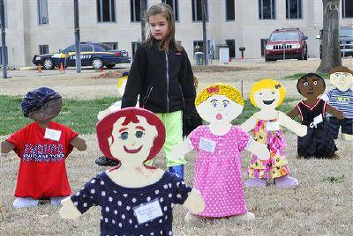 Ryan Fields walks among the 93 wooden kids placed on the Garfield County Courthouse lawn April 1, 2013 in Enid, Okla. by the Garfield Child Advocacy Council for National Child Abuse Prevention Month. Each wooden child represents an abused and/or neglected child in Garfield County. (AP Photo/Enid News & Eagle, Billy Hefton)