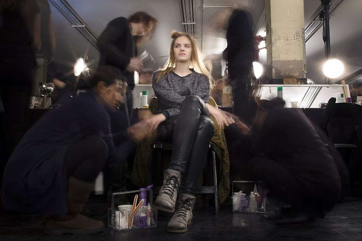 In this photo made with a long exposure, a model is prepared backstage before the Theyskens' Theory Fall 2013 collection is shown during Fashion Week, Monday, Feb. 11, 2013, in New York. (AP Photo/John Minchillo)