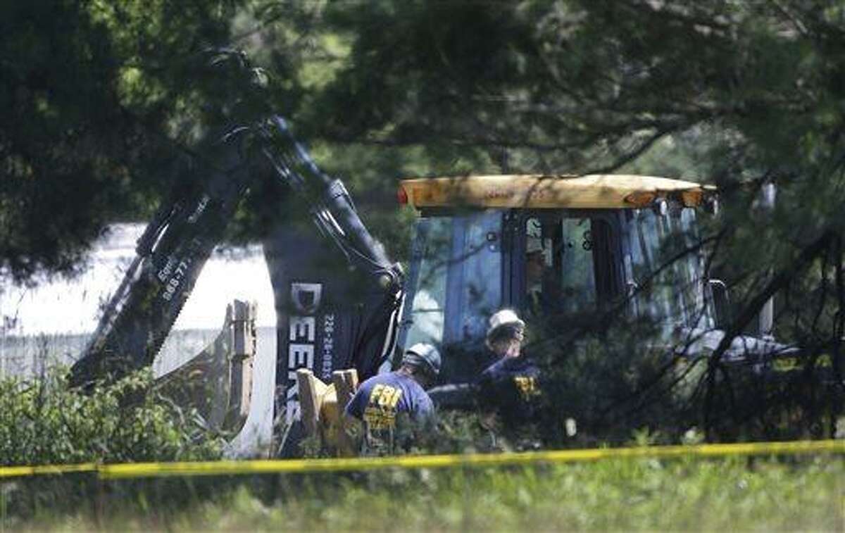 Members of an FBI evidence response team look over an area being cleared in Oakland Township, Mich., Tuesday, June 18, 2013 where officials continue the search for the remains of Teamsters union president Jimmy Hoffa, who disappeared from a Detroit-area restaurant in 1975. (AP Photo/Carlos Osorio)