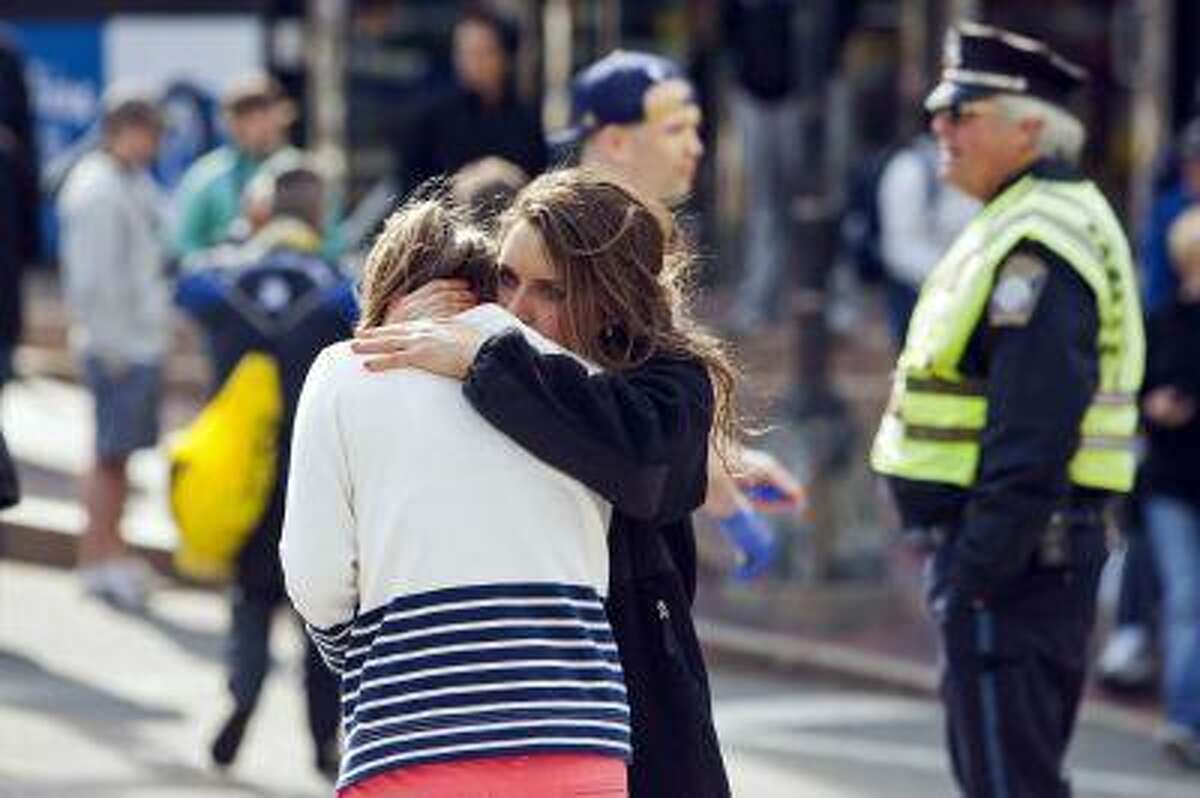 A woman comforts another, who appears to have suffered an injury to her hand, after explosions interrupted the 117th Boston Marathon in Boston, Massachusetts April 15, 2013. Two people were killed and 23 others injured after two explosions struck the Boston Marathon as runners crossed the finish line on Monday, Boston police said. REUTERS/Dominick Reuter (UNITED STATES - Tags: SPORT ATHLETICS DISASTER)