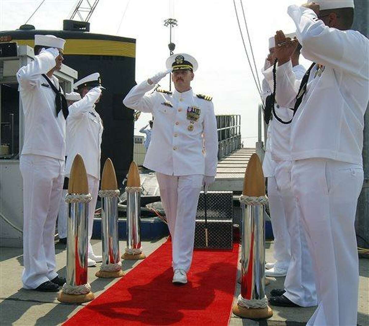 In this Aug. 3, 2012 photo provided by the U.S. Navy, Cmdr. Michael P. Ward II, center, is saluted during the change-of-command ceremony for the nuclear submarine USS Pittsburgh at the Naval Submarine Base New London, in Groton, Conn. Ward was relieved of his command in August 2012 after he faked his own death to end an affair with a woman. Ward's lawyer said Friday, April 12, 2013, during a hearing in Groton to determine his status with the Navy, that Ward admits to the mistake and apologizes, and that he should not be expelled from the Navy. (AP Photo/U.S. Navy, Jason J. Perry )