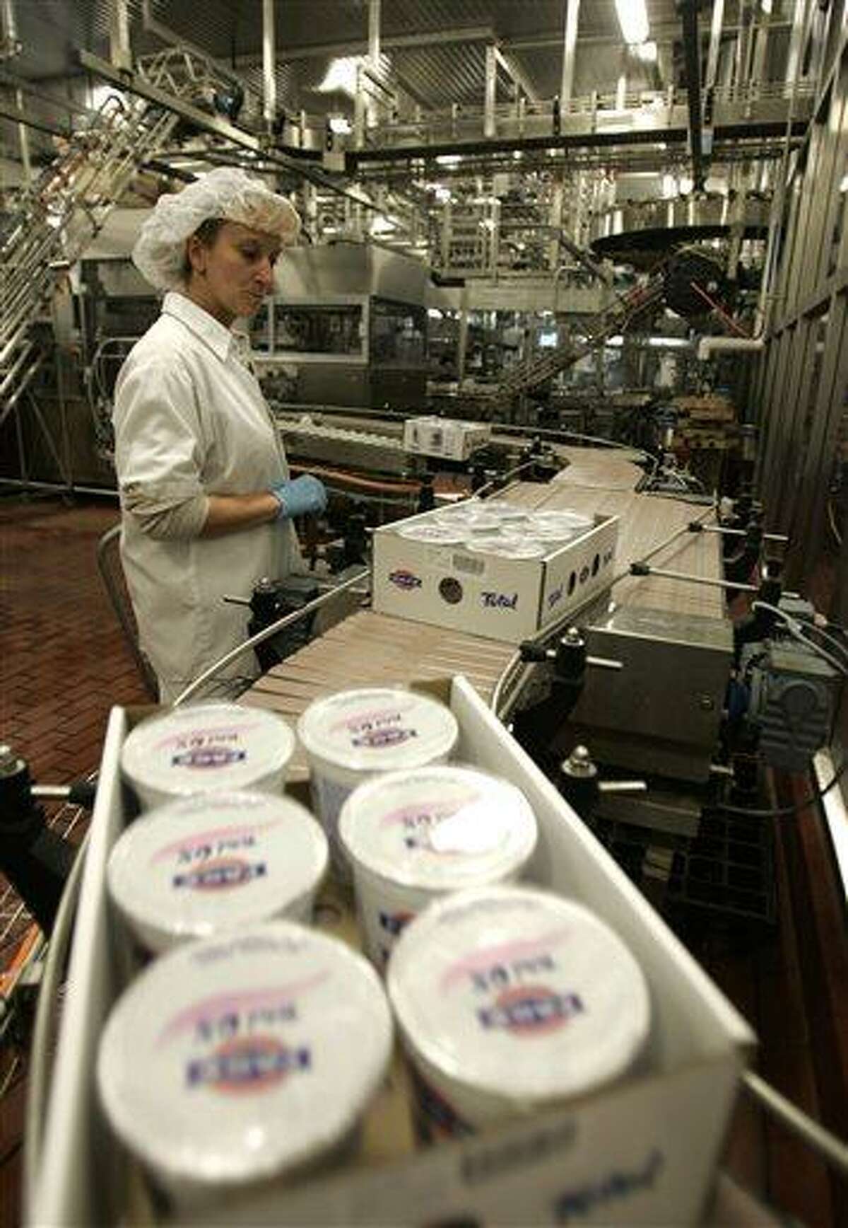 FILE - In this Dec. 10, 2008 file photo, a worker monitors the production line as cases of Fage yogurt are produced in Johnstown, N.Y. Whey, a byproduct of Greek yogurt production, is collected at Gloversville-Johnstown wastewater plant west of Albany, N.Y., and mixed with anaerobic bacteria. The resulting methane gas becomes combustible fuel that generates nearly enough electricity to power the plant. (AP Photo/Mike Groll, File)