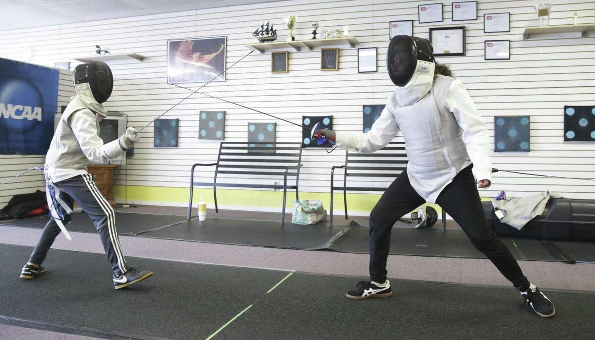 Anna Marie Lopez (right) fences against opponent James Murphy as she works out at the San Antonio Phoenix Fencers’ Club. After surgery to remove a brain tumor left her with multiple medical issues, she took up fencing to return “strength and courage” to her life.