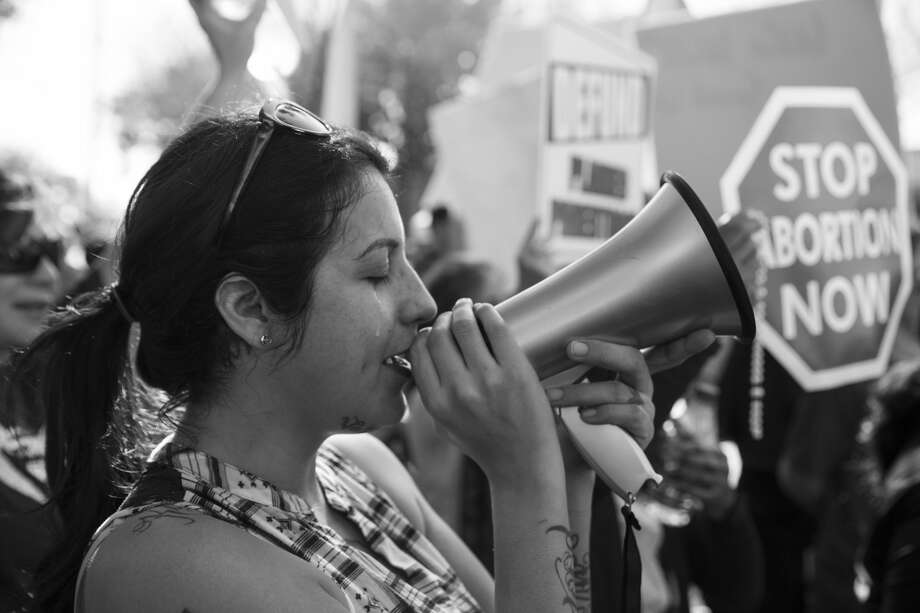 Mercedes Soto cries as she sings a hymn into a megaphone while she and more than a thousand other anti-abortion protestors face off with abortion rights advocates. Photo: Carolyn Van Houten