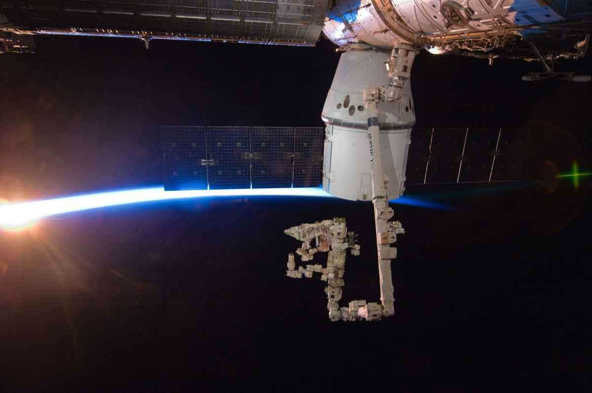 In this image provided by NASA with rays of sunshine and the thin blue atmosphere of Earth serving as a backdrop, the SpaceX Dragon commercial cargo craft is berthed Sunday to the Earth-facing side of the International Space Station's Harmony node. Associated Press