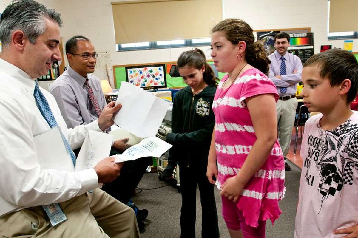 East Haven-Rabith Barakat (L) and Pinith Mar, from DOT, look over a petition presented by 5th graders at Tuttle Elementary School. The students are trying to save a historic bridge. Barakat is a Bridge Engineer. Mar is a Hydrolic Engineer. Students left to right , are Anna Bonitativus, Michaela D'Amato, and Nick Giglietti. Melanie Stenhel/Register