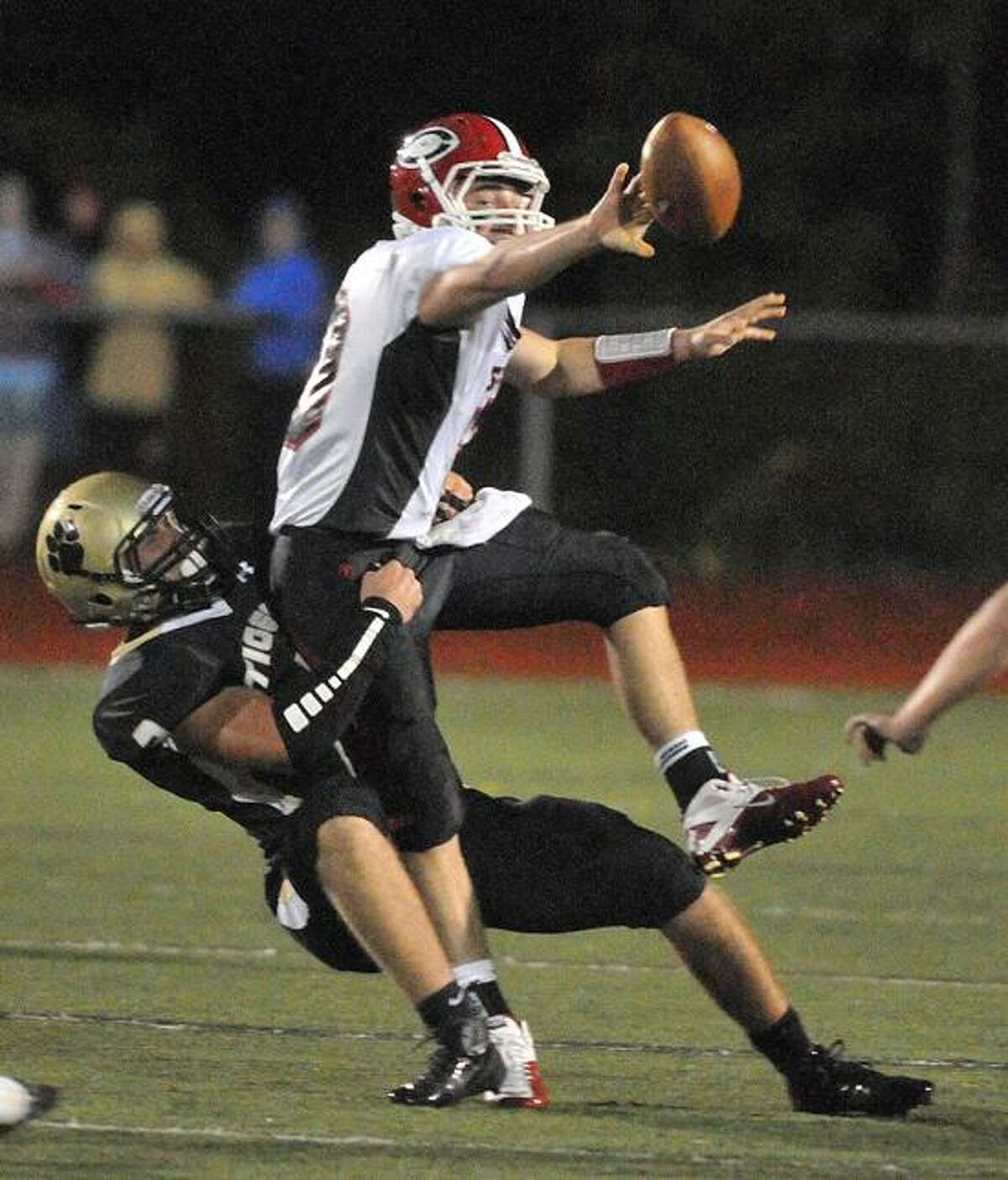 Madison-- Cheshire QB Vincent Sansone tries to pitch the ball at the last minute as Hand's Peter Gerson makes the sack in the first quarter. Photo Peter Casolino/New Haven Register 09/28/12