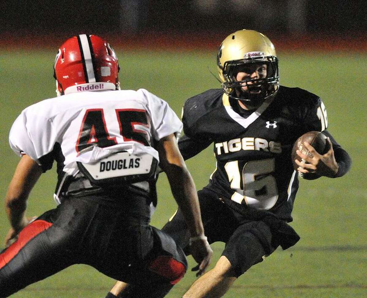 Madison-- Hand's Brendan Bilcheck looks for room as he runs a touchdown in the first quarter of the Tigers' 35-7 victory. Defending for Cheshire is Andrew Yamin. Photo Peter Casolino/New Haven Register 09/28/12