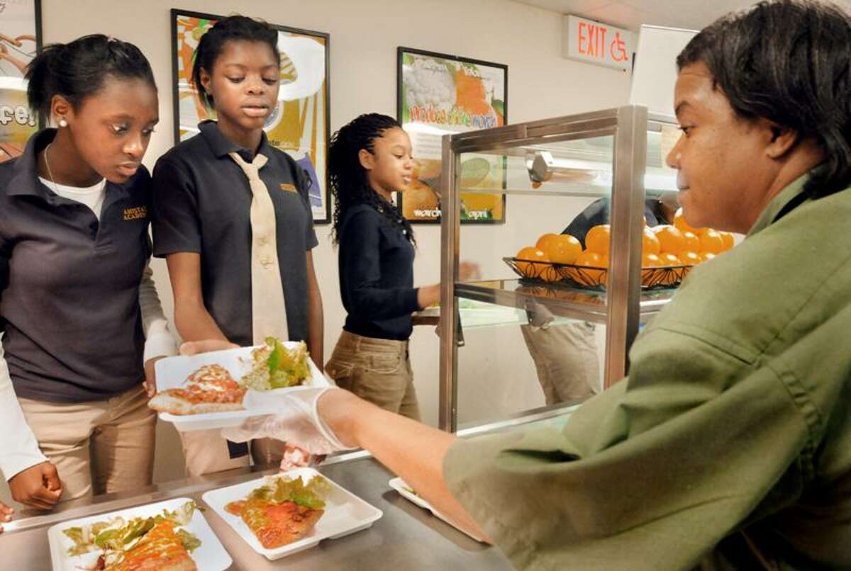 Ranice Caruth, left, and Danah Samuel, center, look over the pizza choices presented by Sharon Heyward as classmate Jasani Thompson takes her selection to the lunchroom. Students had their choice of Cheese, pepperoni, or vegetable deluxe pizza. Melanie Stengel/Register