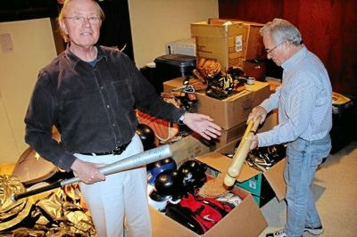 From left: Denis Horgan and Dick Foster browse through boxes of donated baseball gear - uniforms, cleats, gloves, bats, bases, and more - to be transported soon to Miami and then loaded onto a shipping container bound for Cuba. Kathleen Schassler/West Hartford News