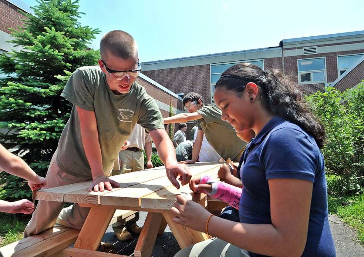 Freshman Carpentry student, Ray Witalis, left, from Emmett O'Brien Technical High School gives instruction to fourth-grader Janeliz Diaz as they sand benches at John G. Prendergast school. The three benches, which were constructed by the O'Brien students, will adorn the Prendergast courtyard. Peter Casolino/New Haven Register
