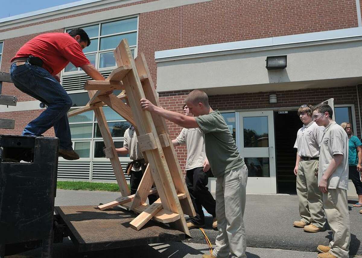 Carpentry students from Emmett O'Brien Technical High School unload benches at John G. Prendergast school, which the students at the high school constructed. The benches will be placed in the Prendergast courtyard. Peter Casolino/New Haven Register