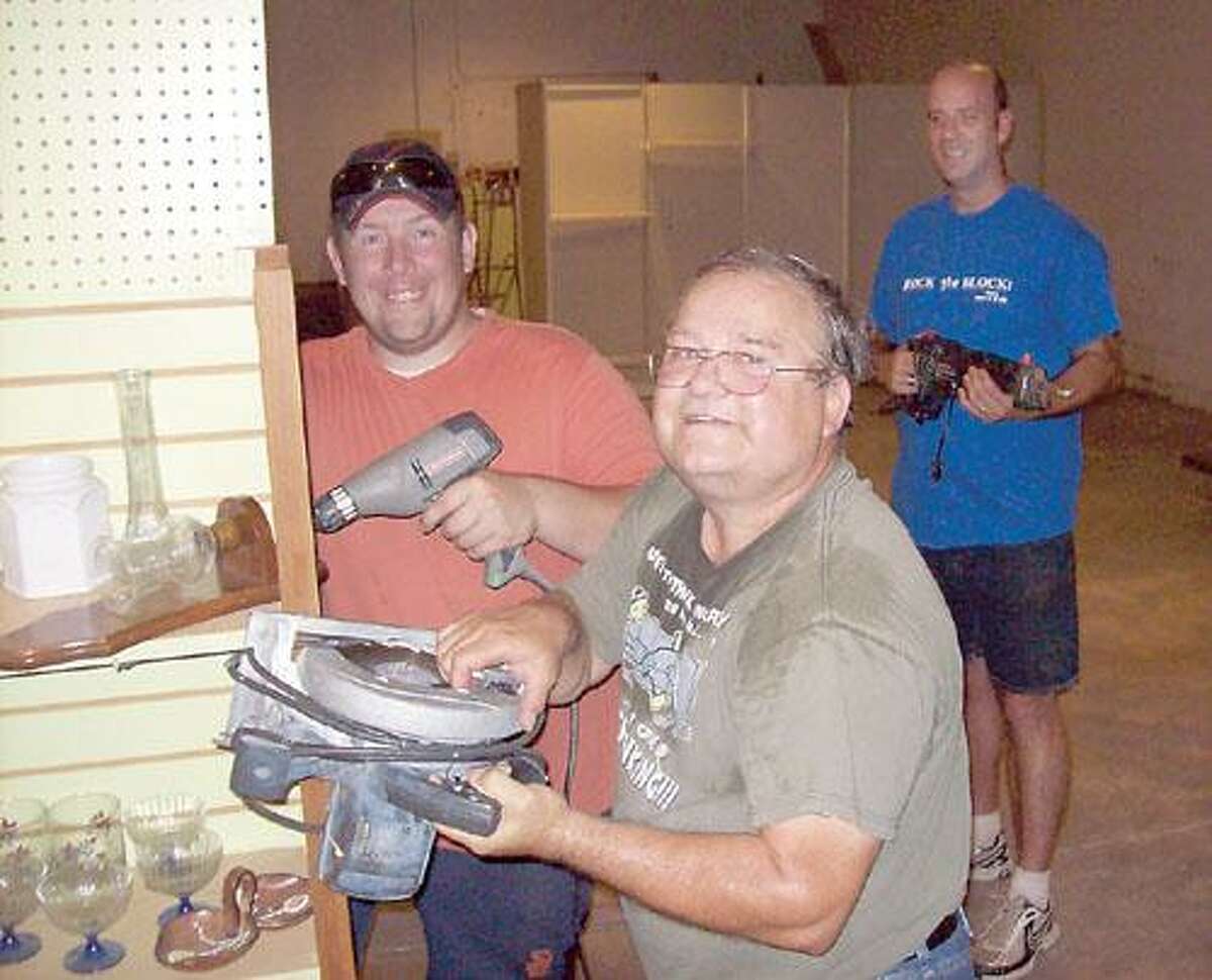 Photo Courtesy Gorman Foundation Volunteers Chris Valerio, left, and John Renfer, center, and Church on the Rock Pastor Jeff Leahey pose with tools they're using to build shelves at the new food pantry at the Oneida church.
