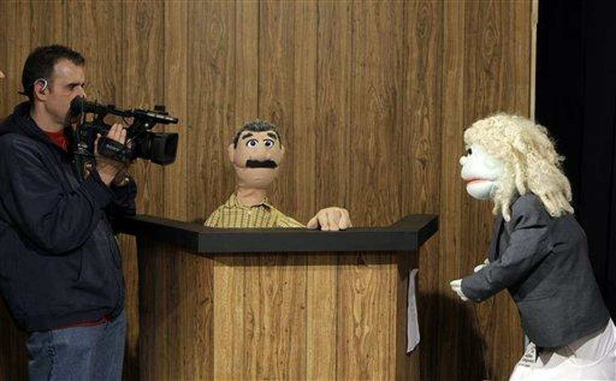 Cameraman Dave Spangler, left, films puppets reenacting testimony in a county corruption trial at the WOIO-TV studios in Cleveland Thursday, Jan. 19, 2012. The station uses the puppets performing as witnesses, reporters and jurors to detail the corruption trial against former Cuyahoga county commissioner Jimmy Dimora, which began last week in federal court in Akron. (AP Photo/Mark Duncan)