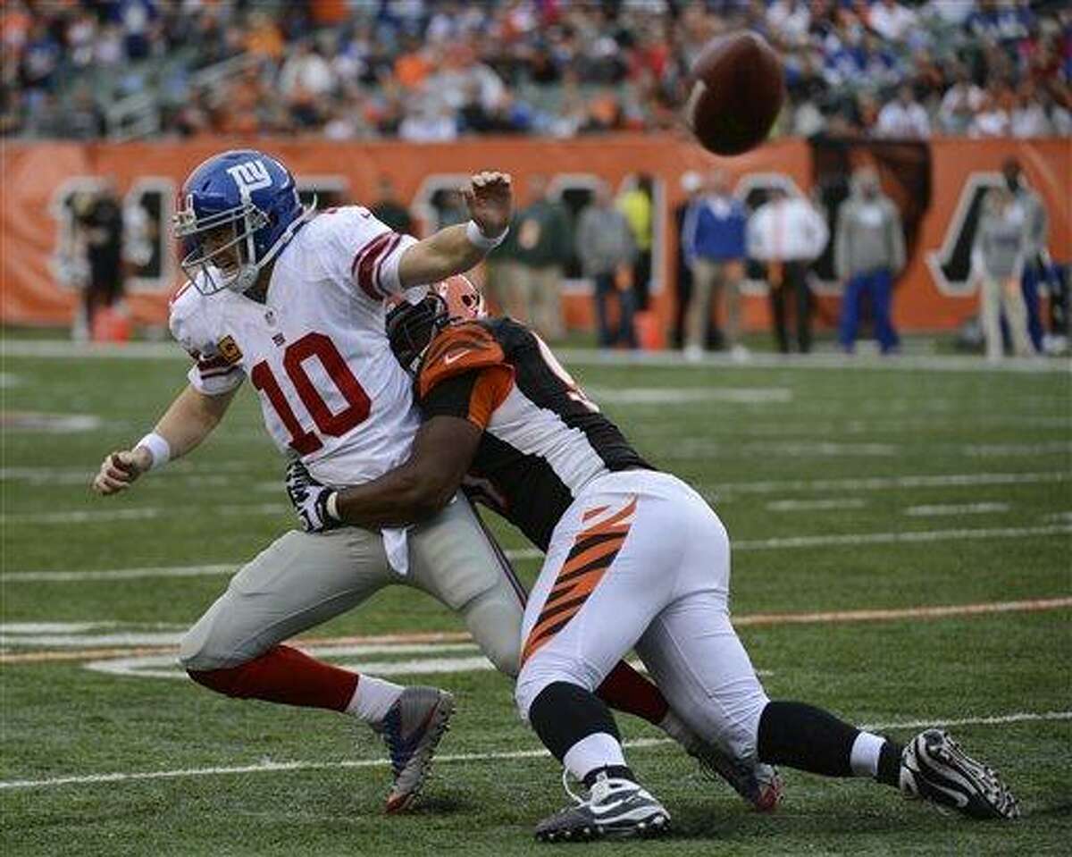 New York Giants quarterback Eli Manning (10) is pursued by Cincinnati Bengals defensive tackle Geno Atkins in the second half of an NFL football game, Sunday, Nov. 11, 2012, in Cincinnati. (AP Photo/Michael Keating)