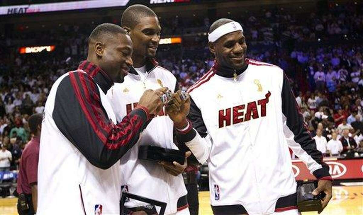 From left, Miami Heat's Dwyane Wade, left, Chris Bosh and LeBron James pose with their 2012 NBA Finals championship rings during a ceremony before a basketball game against the Boston Celtics, Tuesday, Oct. 30, 2012, in Miami. (AP Photo/J Pat Carter)