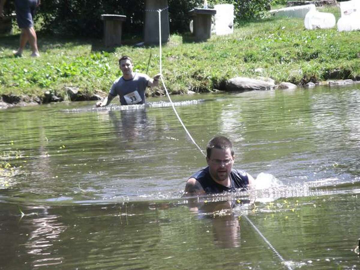 RICKY CAMPBELL/ Register Citizen Racers in the Wyld Mud Run 5K had to trek through a pond Saturday at John A. Minetto State Park, using a rope for guidance, before getting out on the other side. Prior to their dip into the water, participants had to fill buckets and run around a grassy perimeter, holding the buckets.