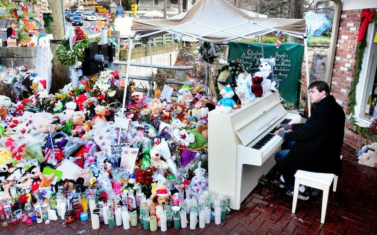 Julian Revie of Ottawa, Canada, plays Christmas music on the piano for visitors to makeshift memorials for the victims of the Sandy Hook Elementary School shootings in downtown Sandy Hook on Christmas 12/25/2012.Photo by Arnold Gold/New Haven Register