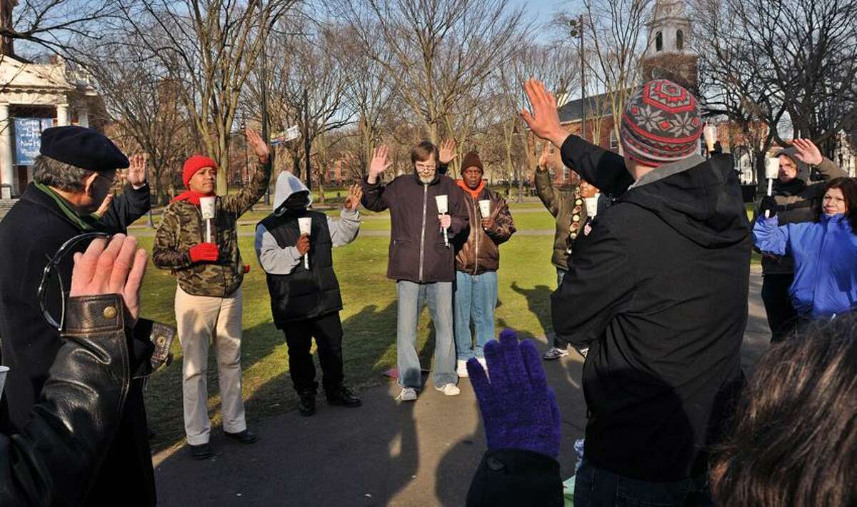 New Haven-- Members of the mental health community lead by Kyle Pedersen, right (facing away), pray during a vigil on the New Haven Green remembering the Sandy Hook shooting victims. Photo-Peter Casolino 12/24/12,
