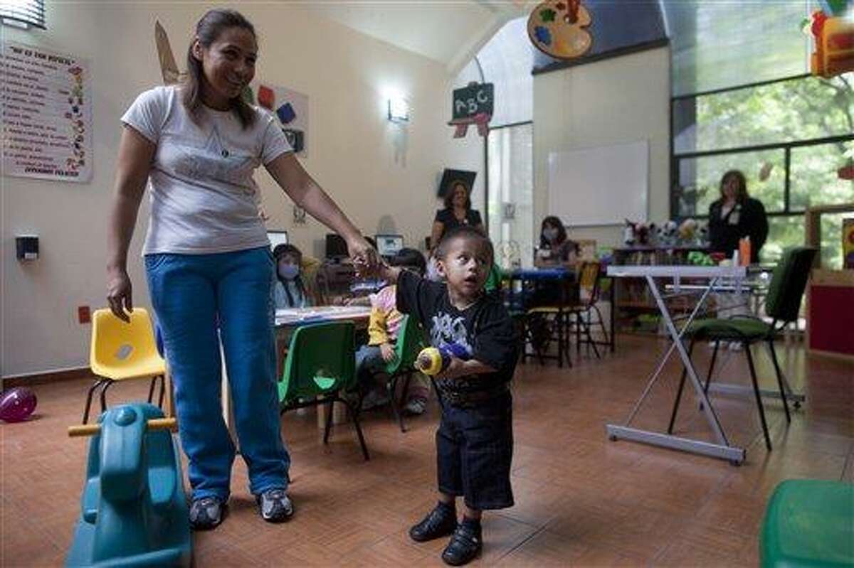 Jesus Rodriguez, 2, holds onto the hand of his mother Maria Fernandez, in a play area of La Raza Medical Center, in Mexico City, Tuesday, June 26, 2012. Mexican doctors successfully removed a 33 pound (15 kg) benign tumor protruding from the boy's right side, connected to the body from the armpit to the hip, and weighed more than Jesus. (AP Photo/Esteban Felix)