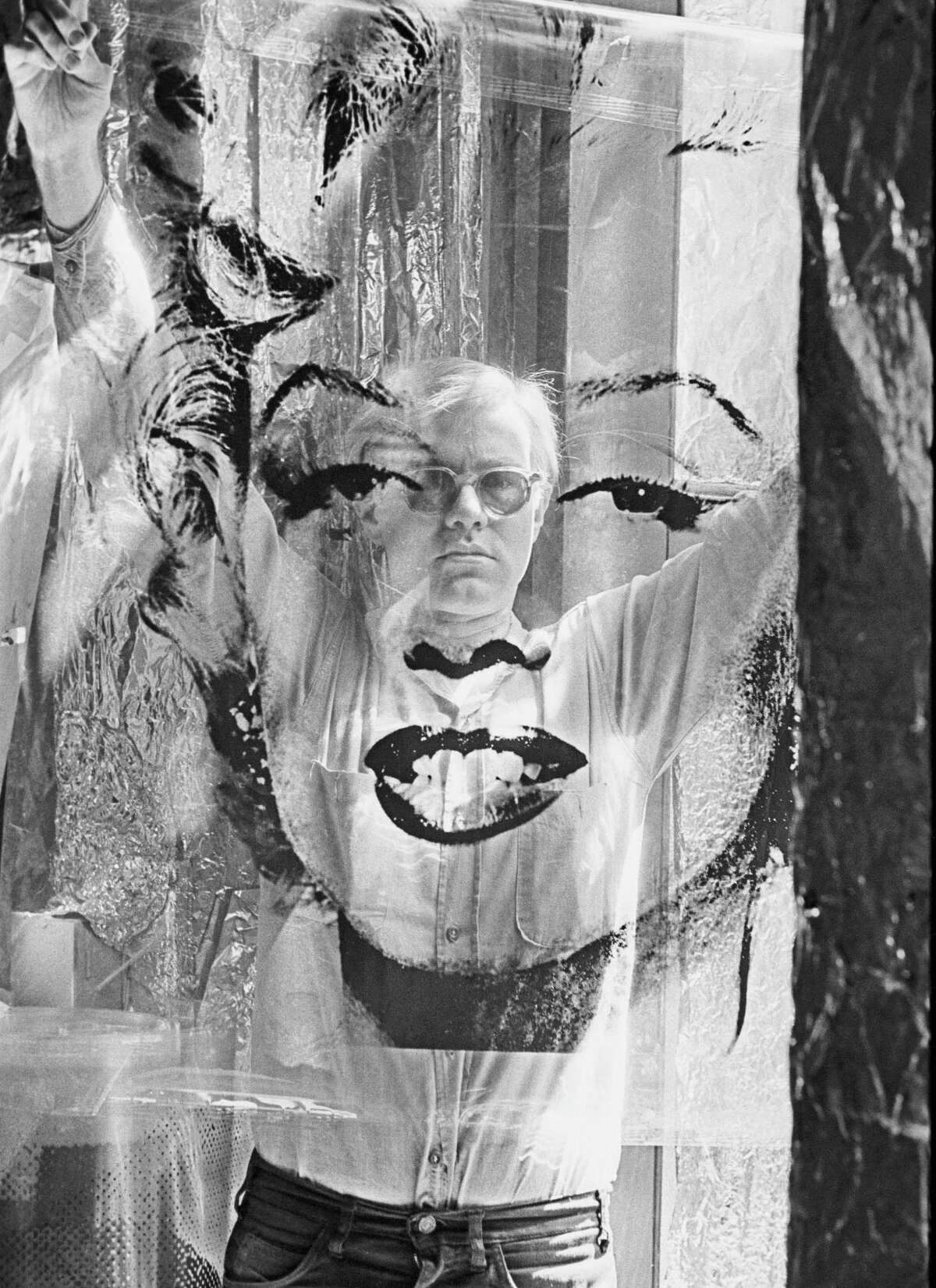 In this 1964 photo provided by Allen Cooper Enterprises, artist Andy Warhol holds an unrolled acetate of "Marilyn" in his New York studio called "The Factory." The photo will be featured in an exhibit entitled: "Before They Were Famous: Behind the Lens of William John Kennedy," which runs through April 29, 2012 at the Site/109 gallery in New York. (AP Photo/William John Kennedy via Allen Cooper Enterprises)
