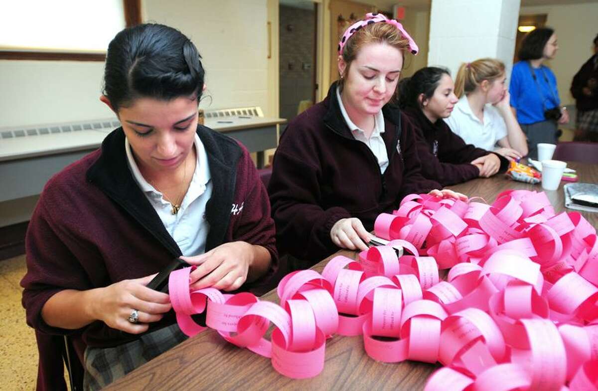 Sacred Heart Academy seniors Nicole Funaro, left, and Maggie McAndrew, center, complete a prayer chain at the school in Hamden. The prayer chain consists of individual paper links with prayers by students for someone they know who is suffering from cancer or who has died from the disease. Photo by Arnold Gold/New Haven Register