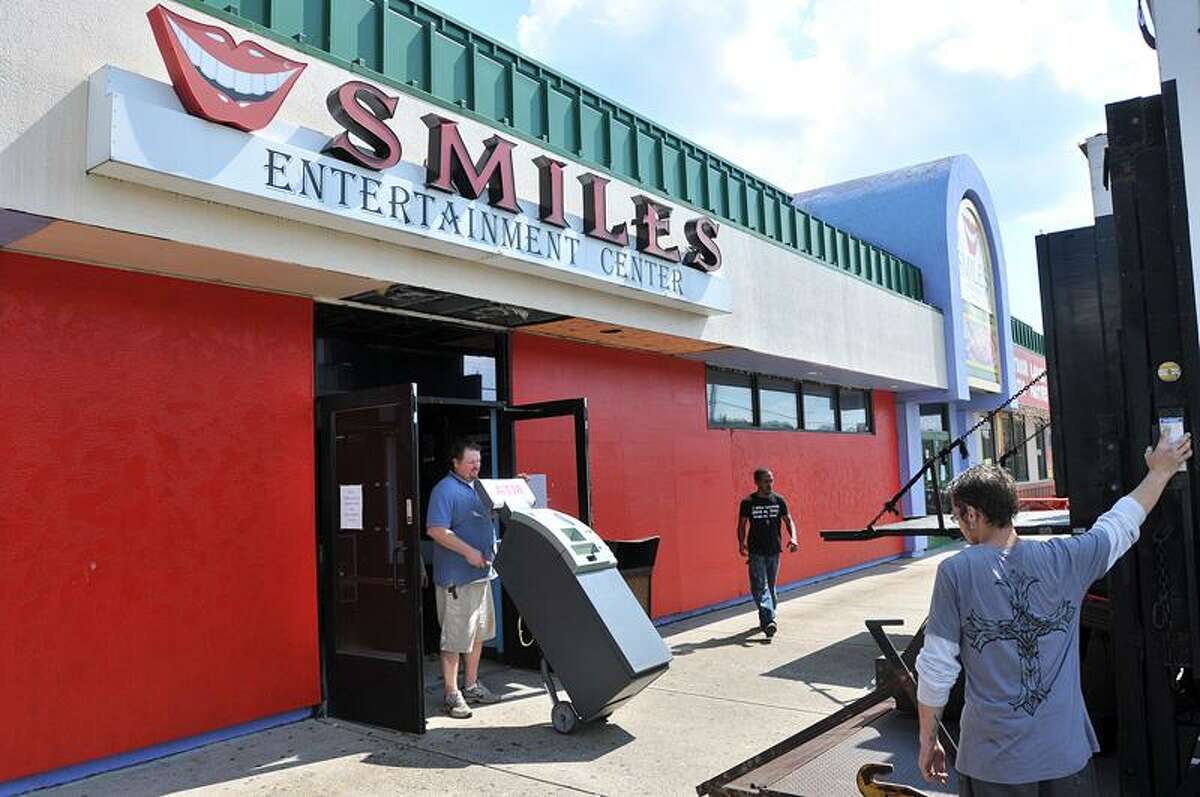Tim Nash, route supervisor for Amusement Consultants Ltd. of New York, which owns Smiles Entertainment Center, wheels out an ATM from the building Wednesday in Milford. Peter Casolino/Register