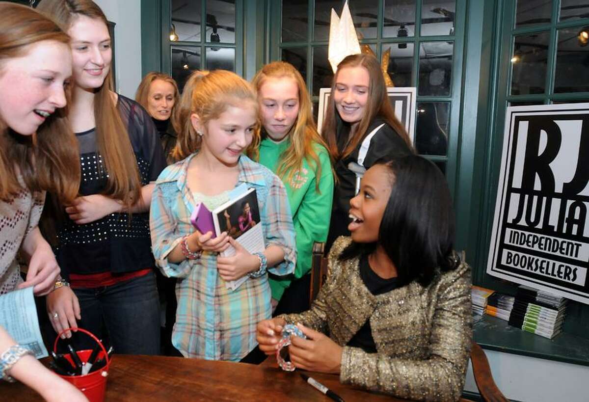 Olympic gold medalist Gabrielle Douglas, right, received handmade bracelets from fans while signing copies of her memoir at RJ Julia Booksellers in Madison Thursday. From left are Meghan, Shannon and Hannah Lewis of Madison; and Deirdre and Bridget Hackett of Guilford. Mara Lavitt/Register