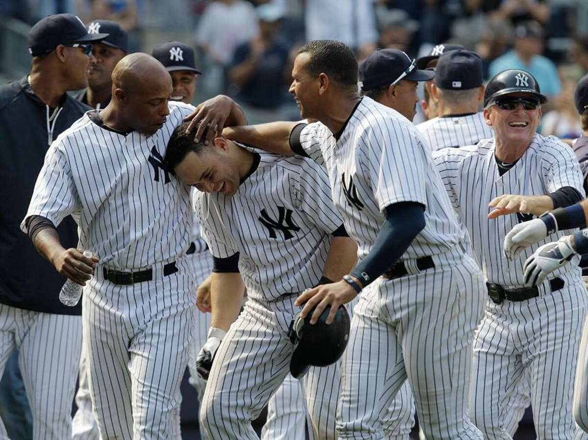 New York Yankees Dewayne Wise, left, and Alex Rodriguez, right, celebrate with the Yankees Russell Martin after Martin hit a ninth-inning, game-winning, walk-off solo home run in the Yankees 5-4 victory over the New York Mets during their baseball game at Yankee Stadium in New York, Sunday, June 10, 2012. First base coach Mick Kelleher reacts, far right. (AP Photo/Kathy Willens)