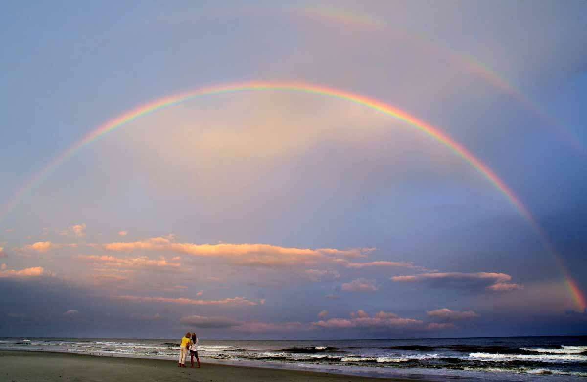 In this photo taken July 30, 2012, beachgoers admire a double rainbow that appeared over Hilton Head Island's South Forest Beach after Monday evening's rains in Hilton Head, S.C. (AP Photo/The Island Packet, Jay Karr)