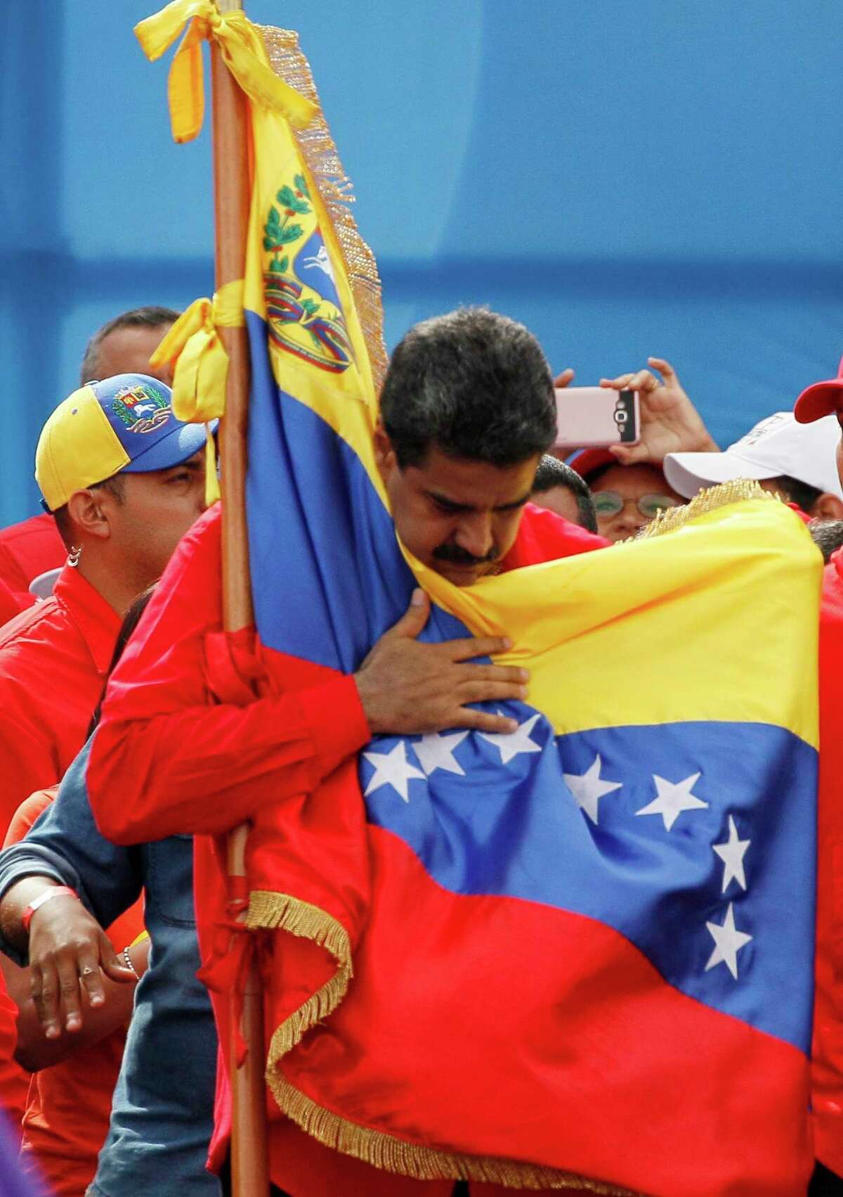 Venezuela's President Nicolas Maduro holds the country's national flag during a rally in Caracas, Venezuela, Thursday, July 27, 2017. President Maduro has provoked international outcry and enraged an opposition demanding his resignation with his push to elect an assembly that will rewrite the troubled South American nation's constitution. Sunday's election will cap nearly four months of political upheaval that has left thousands detained and injured and at least 100 dead. (AP Photo/Ariana Cubillos)