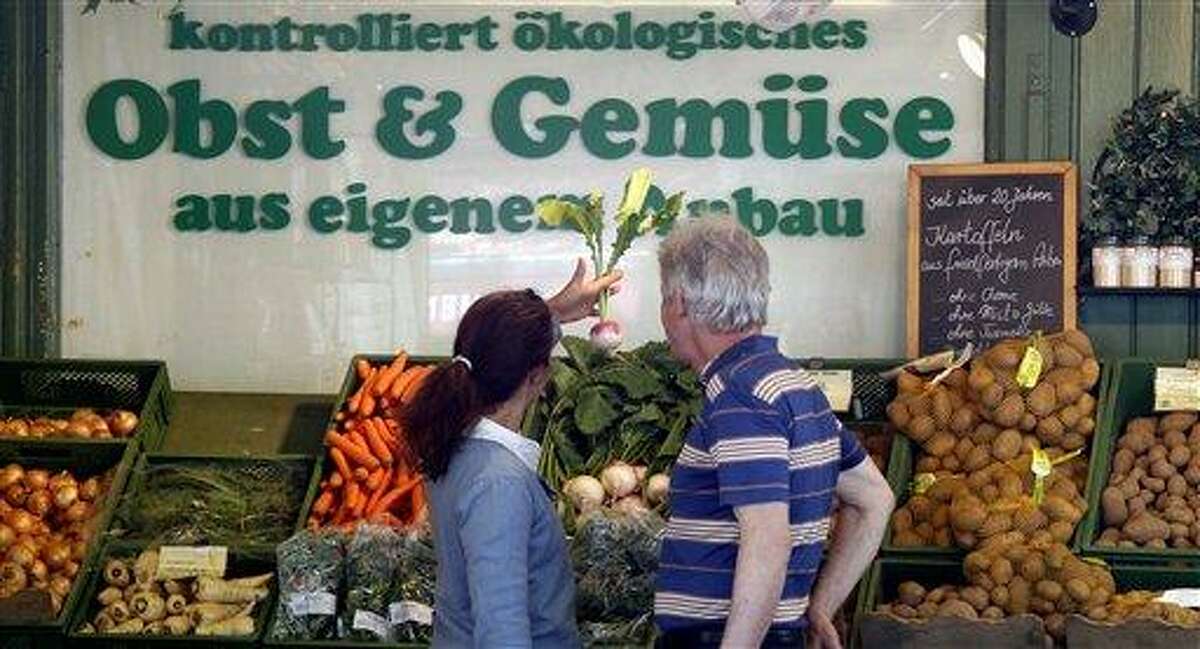 People look at vegetables at a fruit and vegetable market in Munich, southern Germany, on Tuesday, May 31, 2011. Germany's national disease control center says the number of people falling ill in connection with a mysterious bacterial outbreak linked to tainted vegetables continues to rise. Robert Koch Institute said Tuesday that more than 1,150 people have been affected by the bacteria and that it has confirmed nine deaths. Sign in background reads: 'Controlled Organic, Fruit and Vegetables, own growing'. (AP Photo/Matthias Schrader)