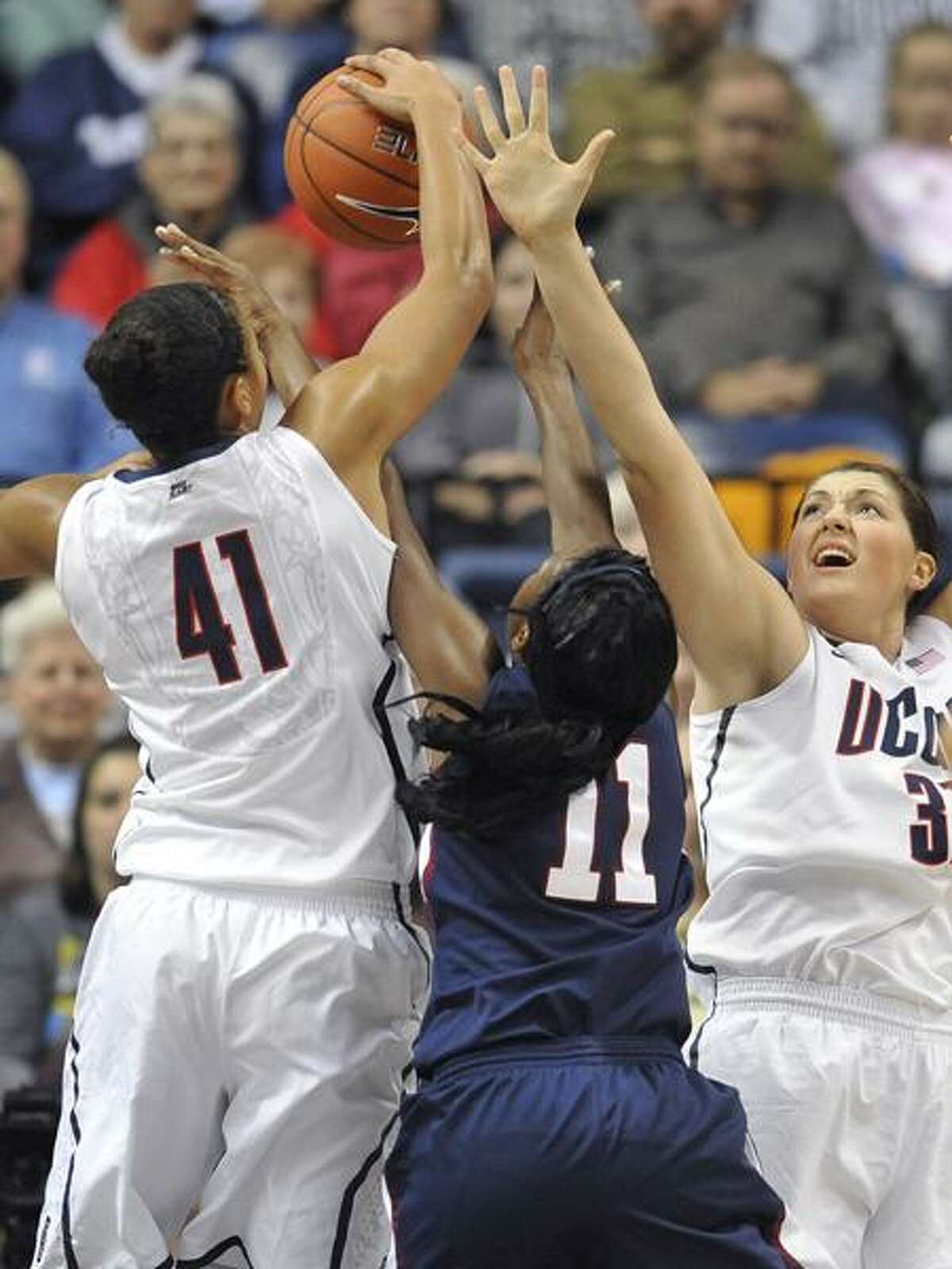 Connecticut's Kiah Stokes (41) blocks a shot from Fairleigh Dickinson's Desiree Crawford (11) as Stefanie Dolson, right, defends in the first half of an NCAA college basketball game in Storrs, Conn., Friday, Nov. 25, 2011. (AP Photo/Jessica Hill)