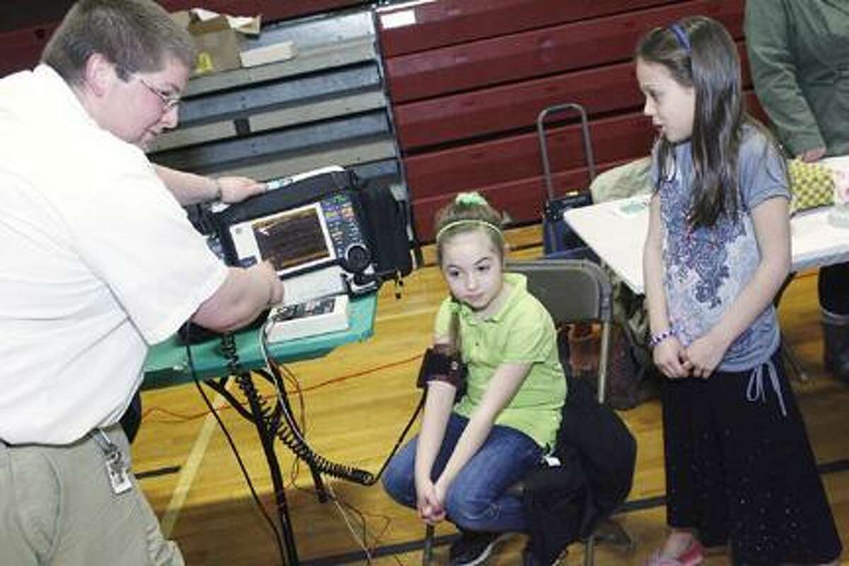 Dispatch Staff Photo by JOHN HAEGERGLAS member Patrick Dwyer shows Olivia Besaw, center, and Karena Hollenbeck a heart monitor during the annual Health and Wellness Fair held in Canastota on Thursday, March 17, 2011.