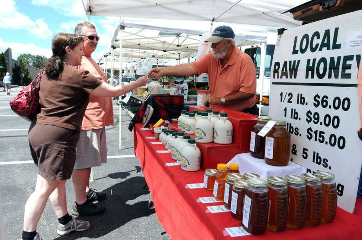 The Tanger Factory Outlets Center in Westbrook is holding a farmer's market Thursdays from 11 a.m to 3 p.m. Lydia Pozillo, left, and Ray Gorneau, center, both of Clinton sampled some of Chuck Haralson's offerings from his Sugar Maple Farms in Lebanon. Mara Lavitt/Register photos