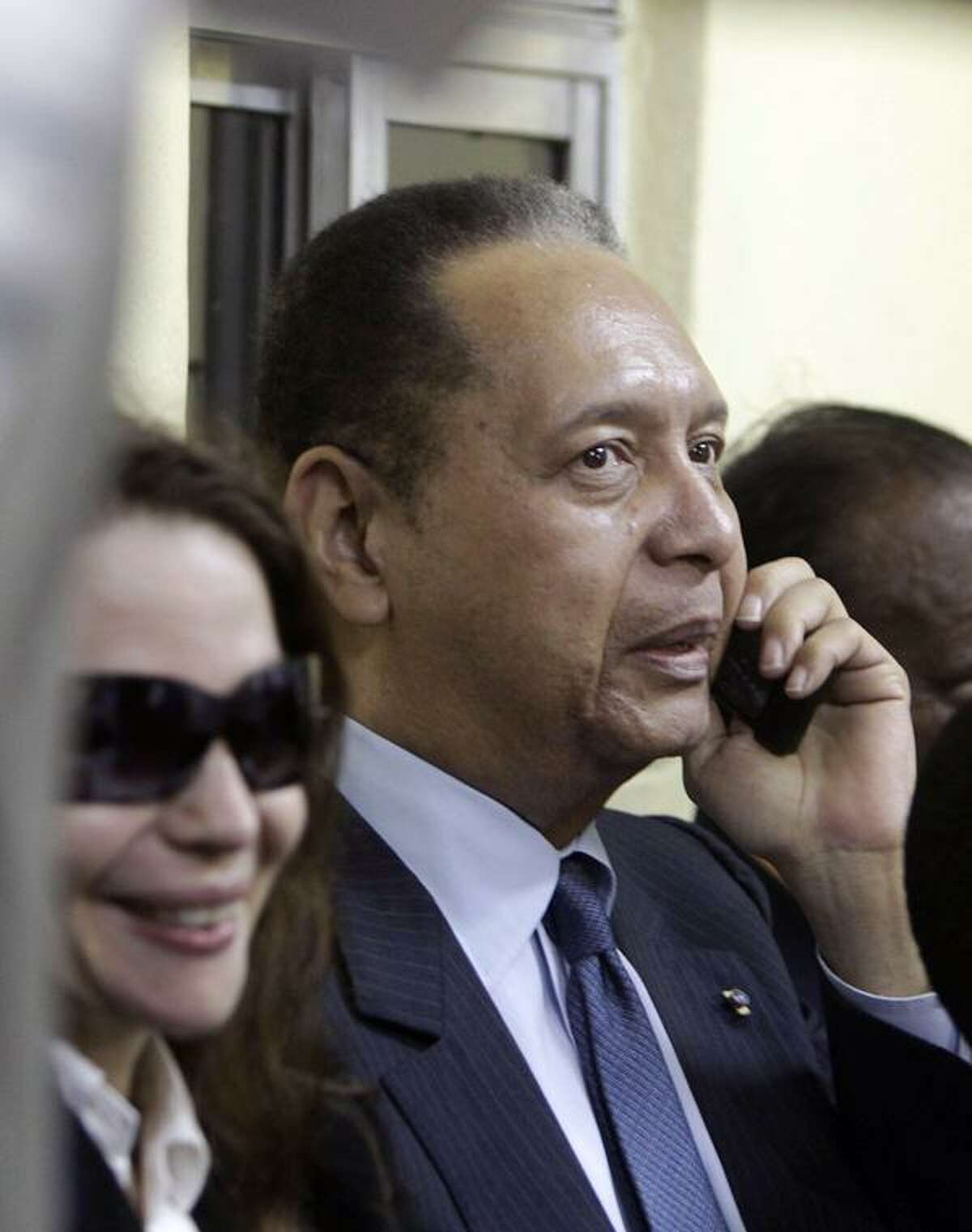 Former Haitian dictator Jean-Claude "Baby Doc" Duvalier talks by phone next to his wife Veronique Roy upon his arrival to the Toussaint Louverture international airport in Port-au-Prince, Haiti, Sunday Jan. 16, 2011. Duvalier returned Sunday to Haiti after nearly 25 years in exile, a surprising and perplexing move that comes as his country struggles with a political crisis and the stalled effort to recover from last year's devastating earthquake. (AP Photo/Dieu Nalio Chery)