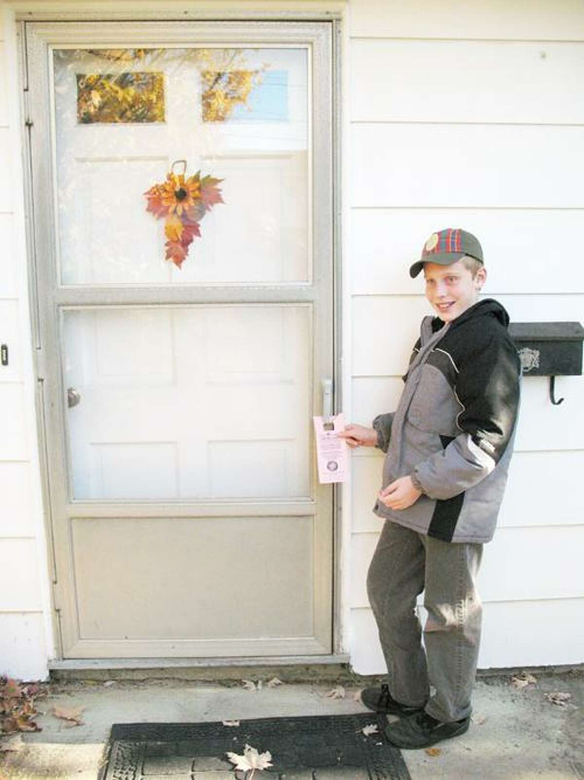 SUBMITTED PHOTO Scout Harry Jones hangs up reminder tags for the Scouting for Food campaign. Boy Scouts and Cub Scouts delivered them on Saturday, Nov. 5.