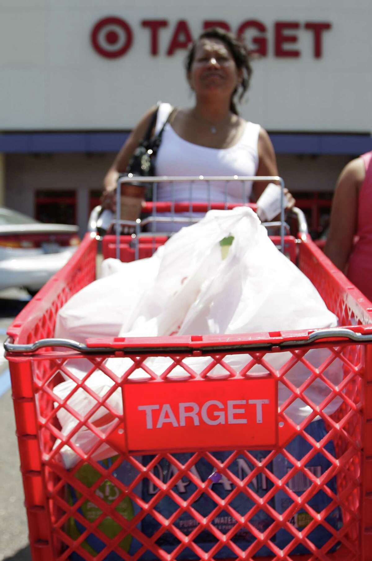 Maria Villalobos pushes a shopping cart out of a Target store after shopping Wednesday in San Diego. (AP Photo/Gregory Bull)