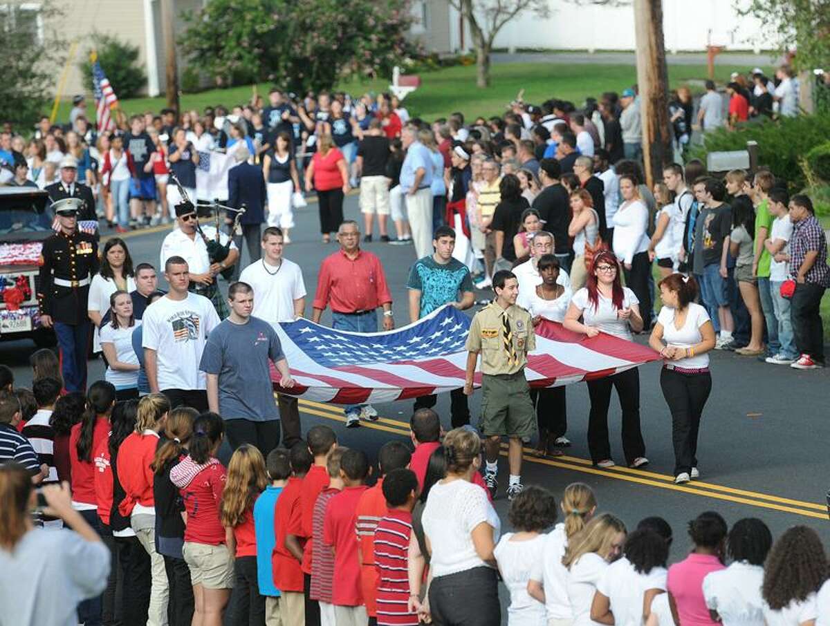 Flag bearers carry a large U.S. flag past thousands of students from various schools in Ansonia. Peter Casolino/Register