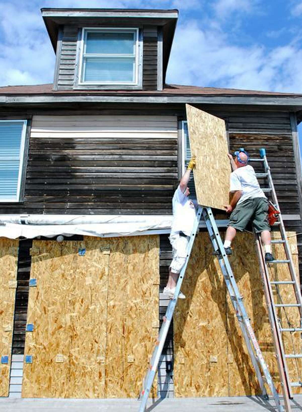 Frank Odice (right) and Scott Brewer (far right) of Affordable Handyman of Connecticut board up windows with plywood in the back of a home on East Broadway in Milford on Friday 8/26/2011. The home is located on the beach next to Silver Sands State Park and faces the Long Island Sound. Photo by Arnold Gold/New Haven Register