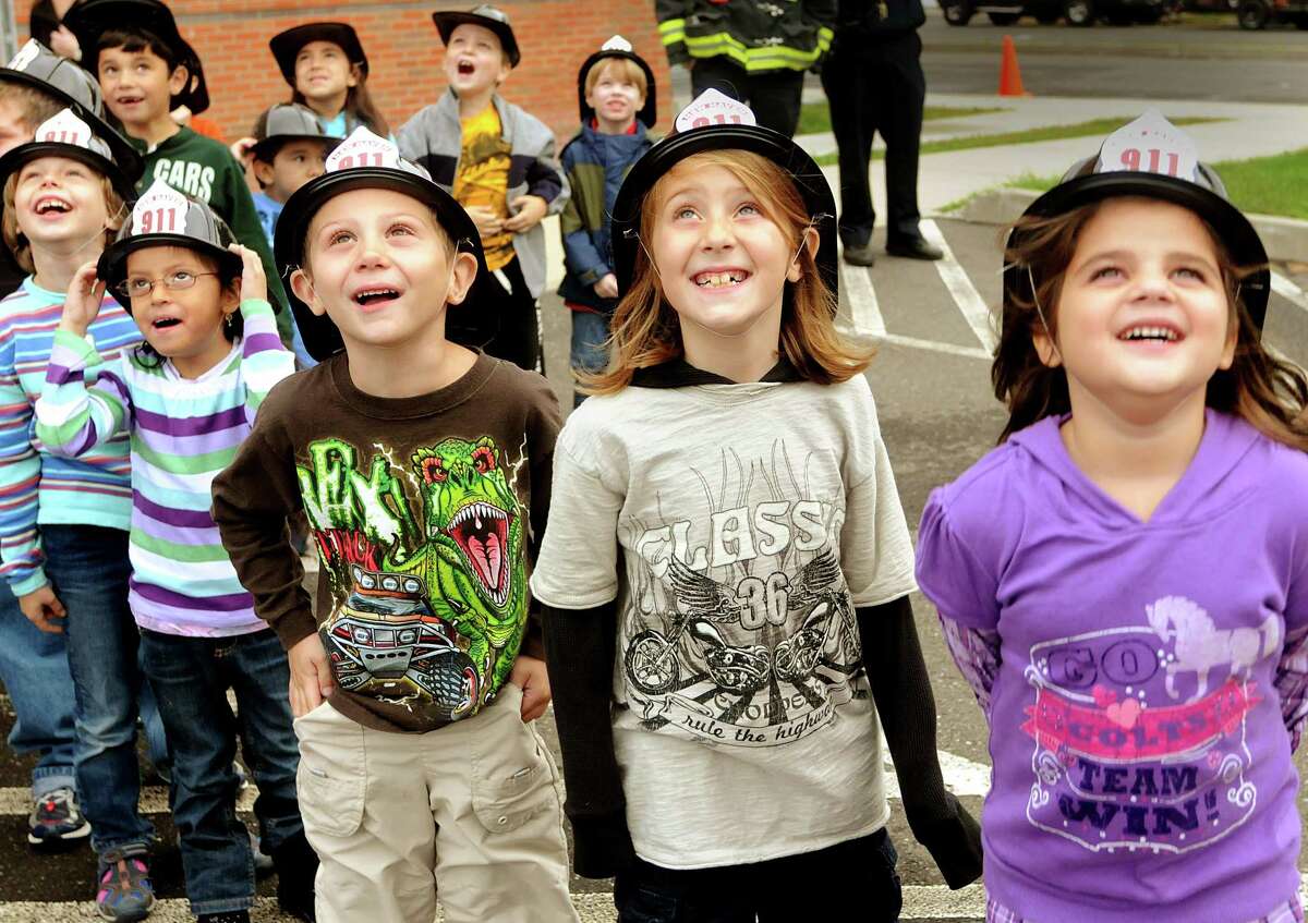 Front, l to r: Clara Rahner, Amelia Flores, Dillion Ridgeway, Erica Collenese, and Amilia Santanelli watch as New Haven firefighters in a hook and ladder truck bucket, rise above their school. They are all 1st graders at Nathen Hale Elementary School. Melanie Stengel/Register
