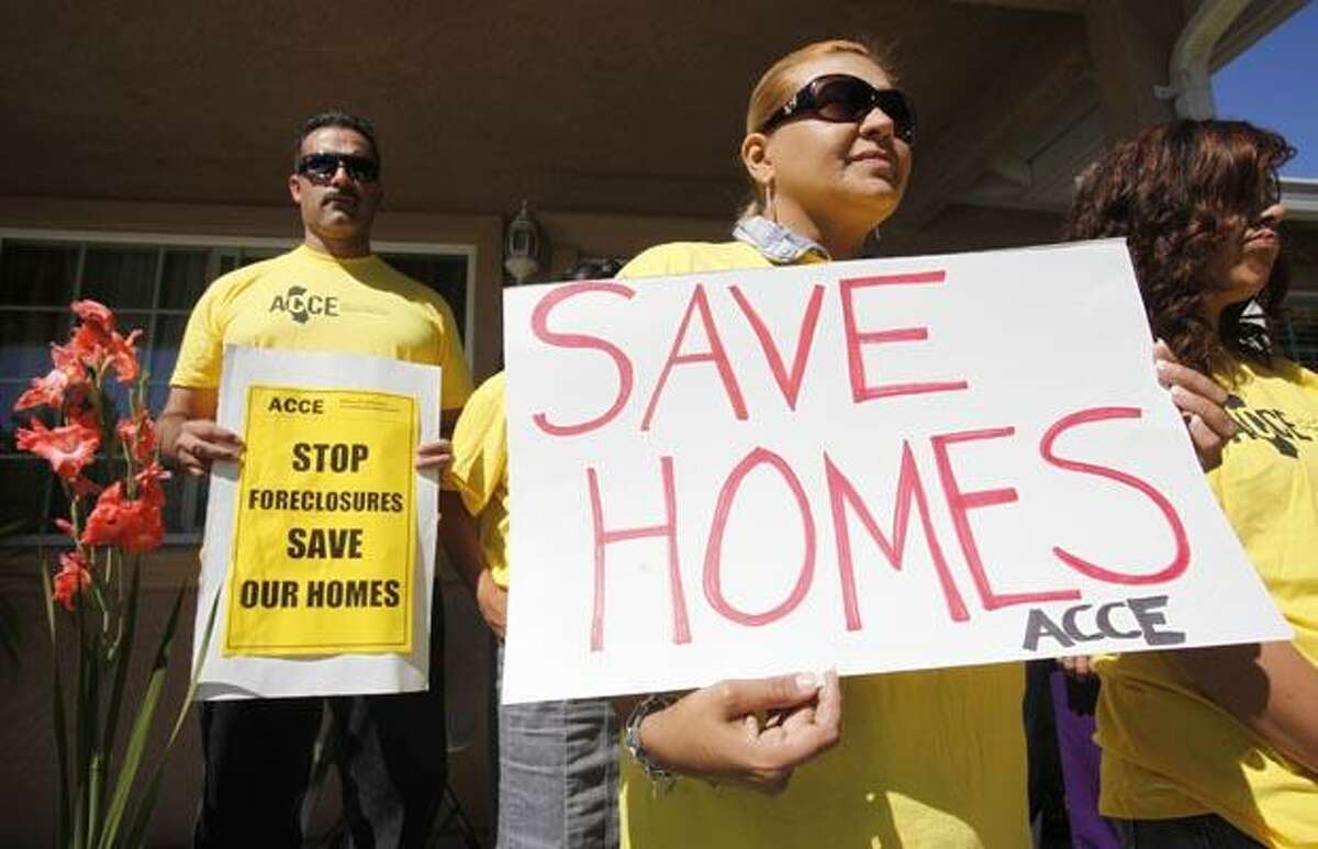 In this Sept. 24, 2010 photo, supporter Marisa Salas, right, holds a sign during a foreclosure and eviction rally at the home of Carlos Moreno in Menlo Park, Calif. Moreno has owned his home since 2006, had his home under foreclosure since January 2010, and was served eviction notice in July 2010. His case is now pending with the bank. For most Americans at risk of losing their homes, the brutal business of foreclosure goes on. (AP Photo/Paul Sakuma)
