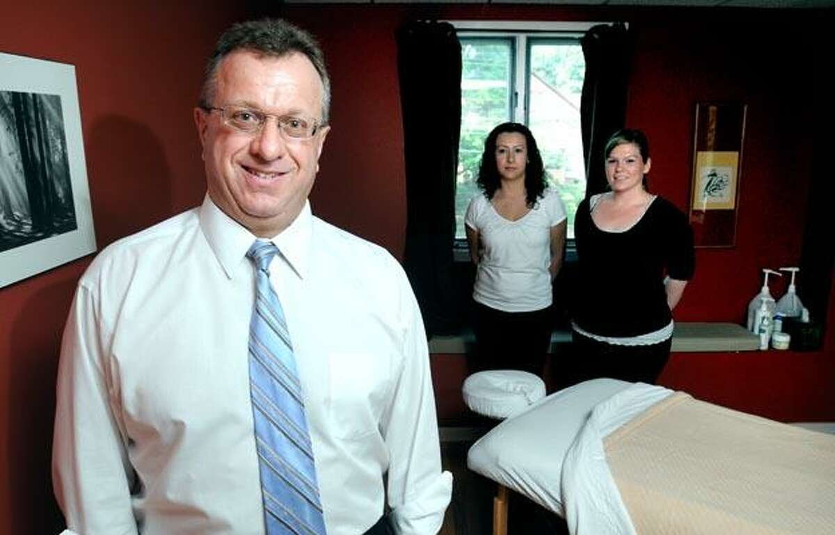 From left, Robert M. Denes and licensed massage therapists Elcy Pareja and Jessica Nieves-Diaz show off one of two massage rooms that Denes has added to his chiropractic business in Hamden. (Arnold Gold/Register)