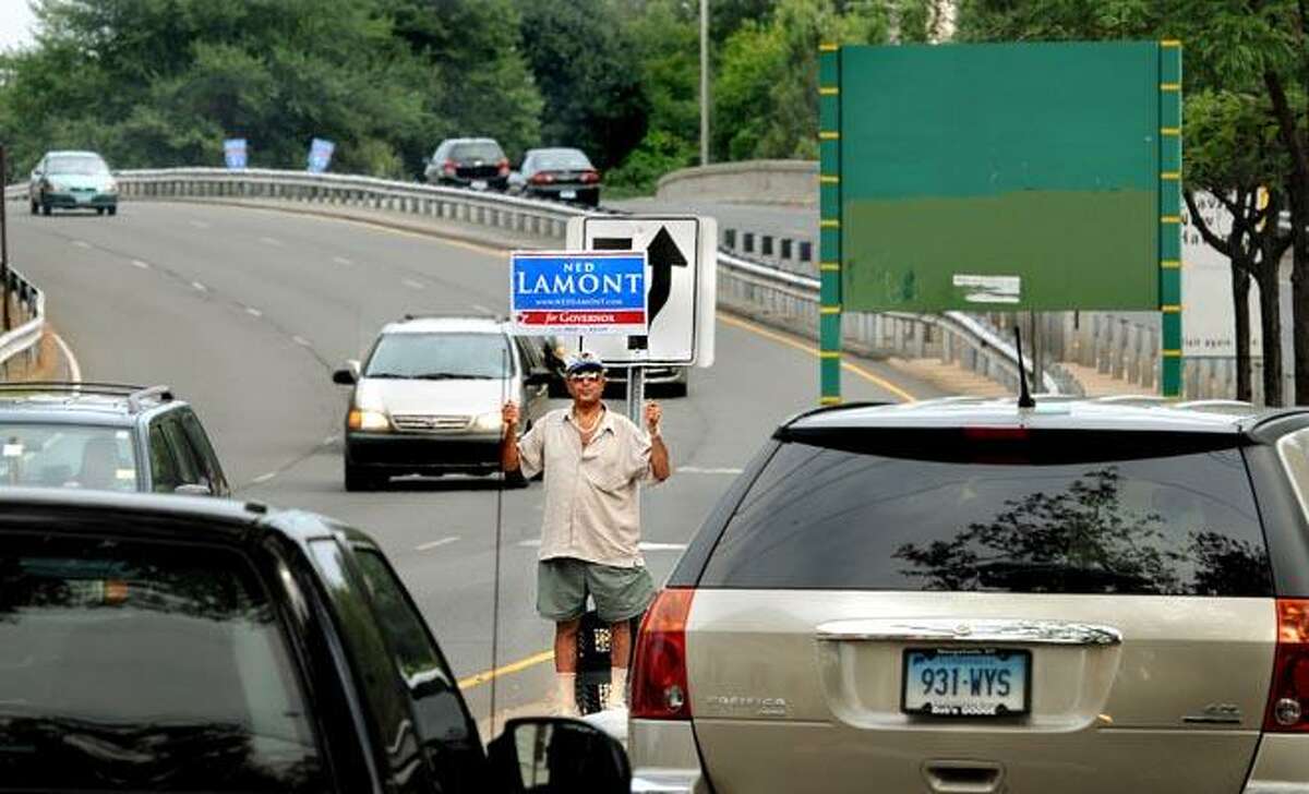 Bulent Ozalp of New Haven holds up a sign supporting Ned Lamont for governor, as he stands at the Interstate 91 entrance at the intersection of Trumbull and Orange streets Monday. Ozalp is a volunteer at Lamont's Orange Street office. (Melanie Stengel/Register)