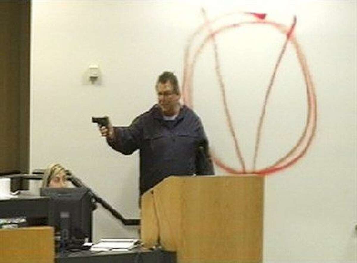 In this image taken from video and released by WJHG-TV, Clay A. Duke points a hand gun at Bay City school board members and staff, Tuesday, Dec. 14, 2010. Duke, a 56-year-old ex-convict, calmly held the school board at gunpoint and said he was seeking redress for his wife's firing before shooting at the superintendent at short range and then killing himself. (AP Photo/WJHG-TV)
