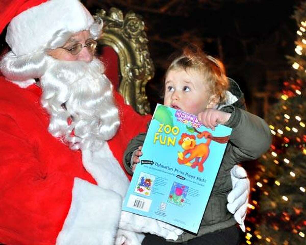 New Haven--Luca Ingles, 2, of New Haven, seems to be a little unsure of Santa, aka Bob Frew of the Upper State Association. Ingles met Santa, who arrived by fire truck, at the Upper State Street Craft Fair and Tree Lighting festivities. Melanie Stengel/Register12/11/10
