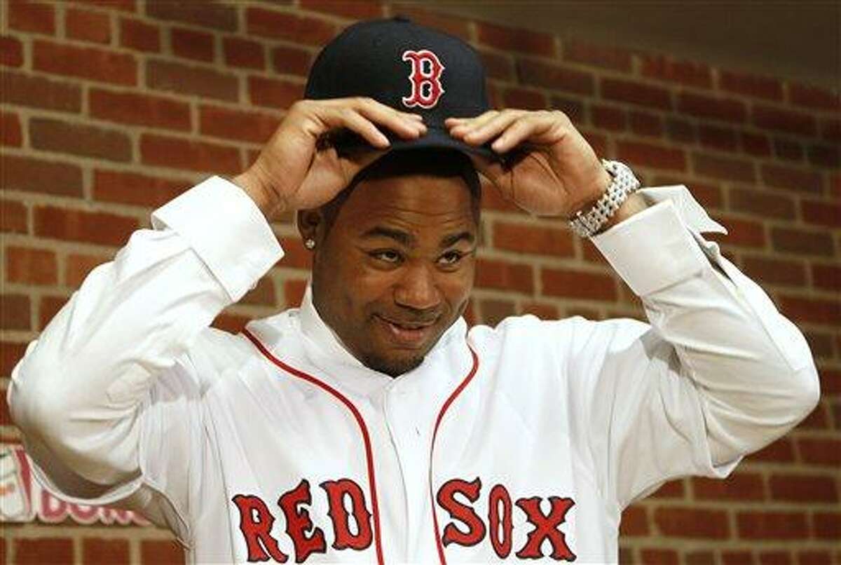 Carl Crawford tries on his new hat during a news conference announcing his signing by the Boston Red Sox baseball club at Fenway Park in Boston Saturday, Dec. 11, 2010. (AP Photo/Winslow Townson)