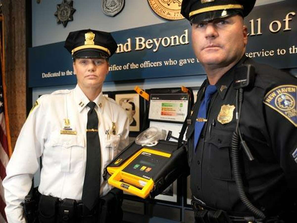 New Haven police Capt. Joann Peterson, left, and Sgt. John Magoveny with the defibrillator they used to save a stricken man at police headquarters. (VM Williams/Register)