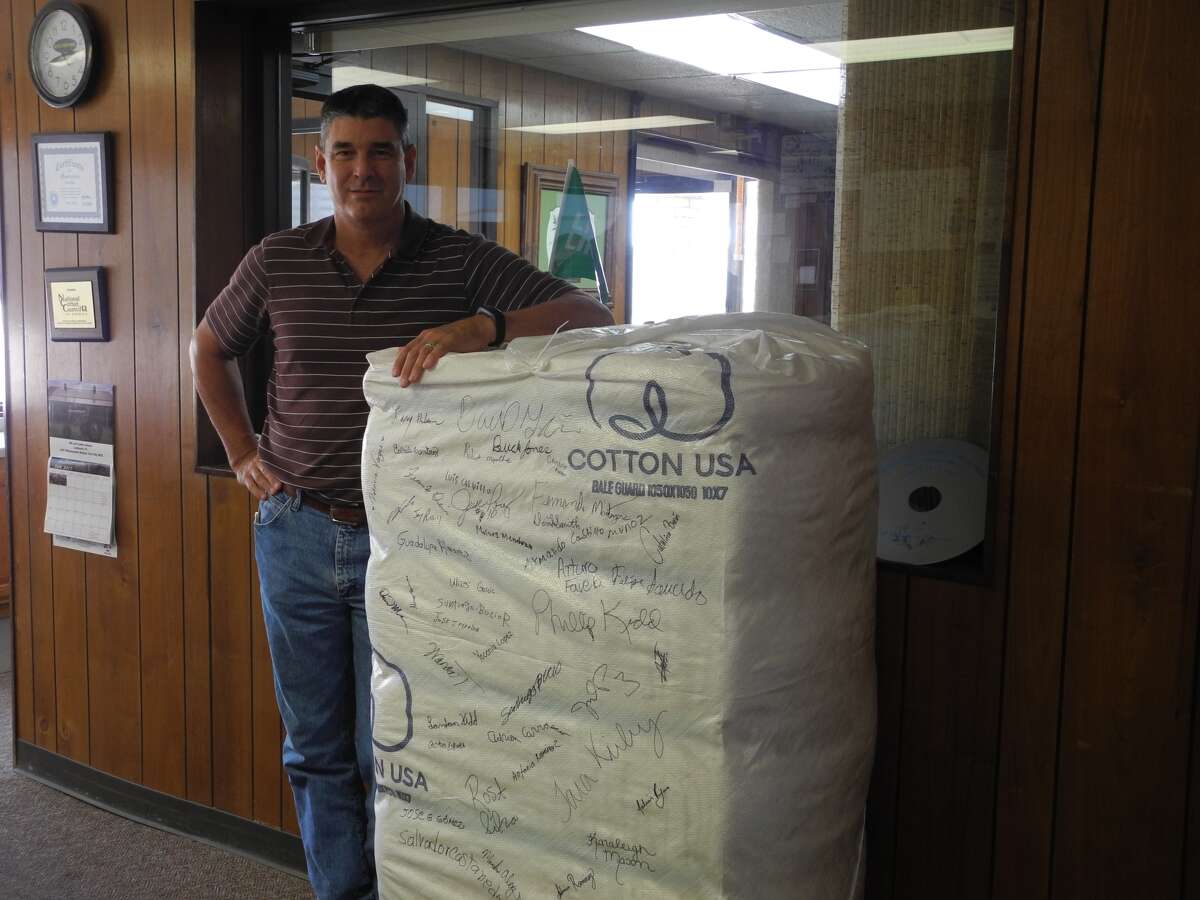 Phillip Kidd, gin manager, stands beside the millionth cotton bale ginned at Edcot Gin in Edmonson. The scanner tag on the lower right corner of the cotton bale shows the location of the ginner and farm, down to the field where it was harvested.